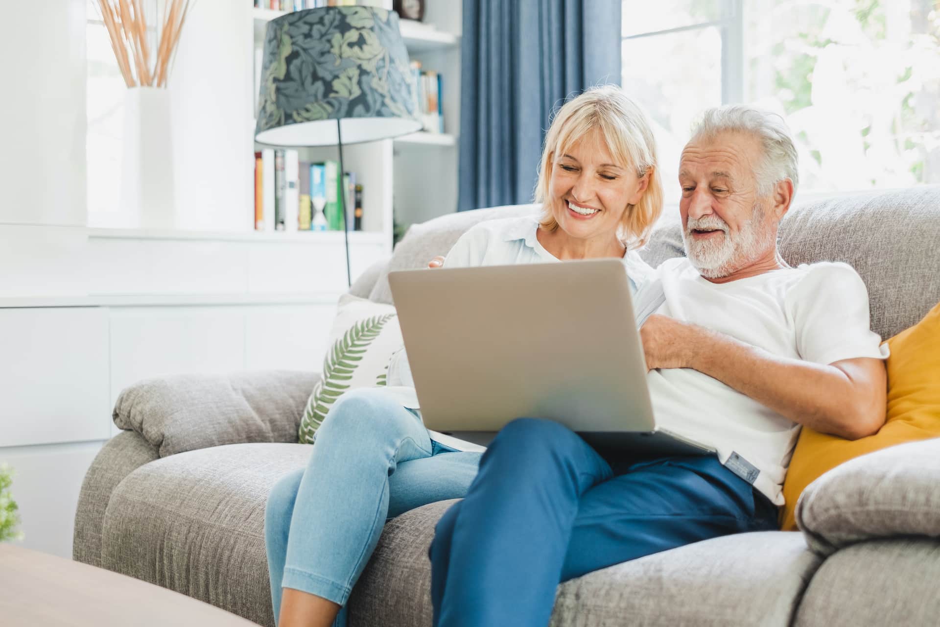 Couple senior using computer laptop on sofa at home for online shopping, surfing internet